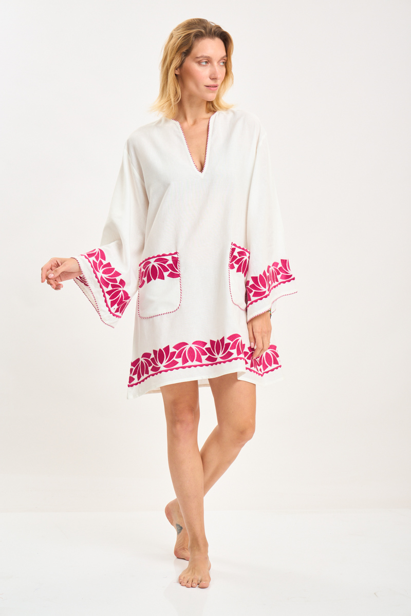 Model wearing a white embroidered kaftan with fuchsia lotus detailing